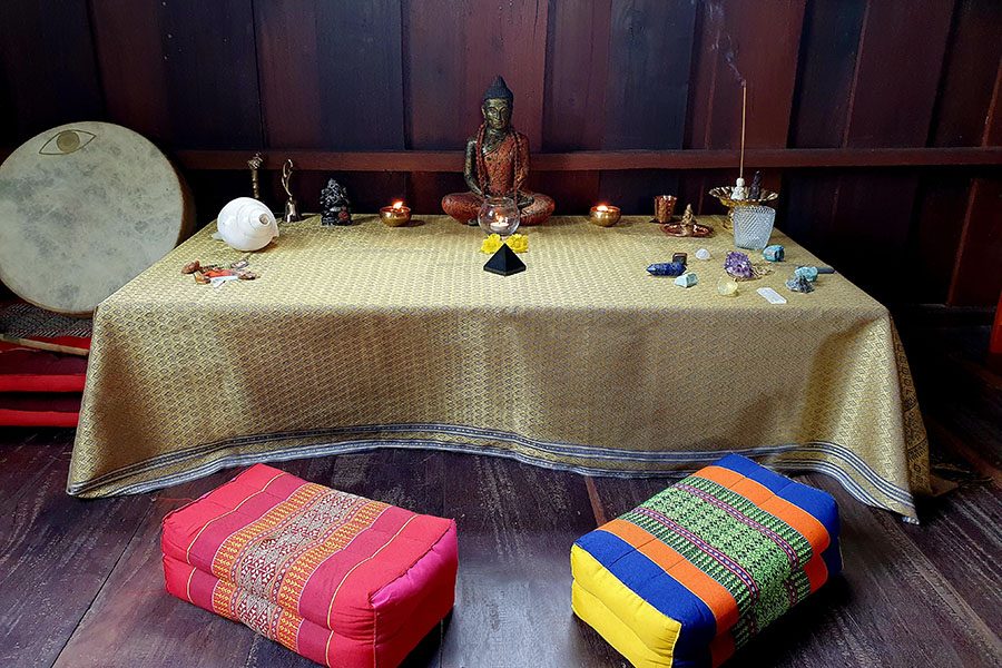 A table covered with a tablecloth holds items used for meditation in India.